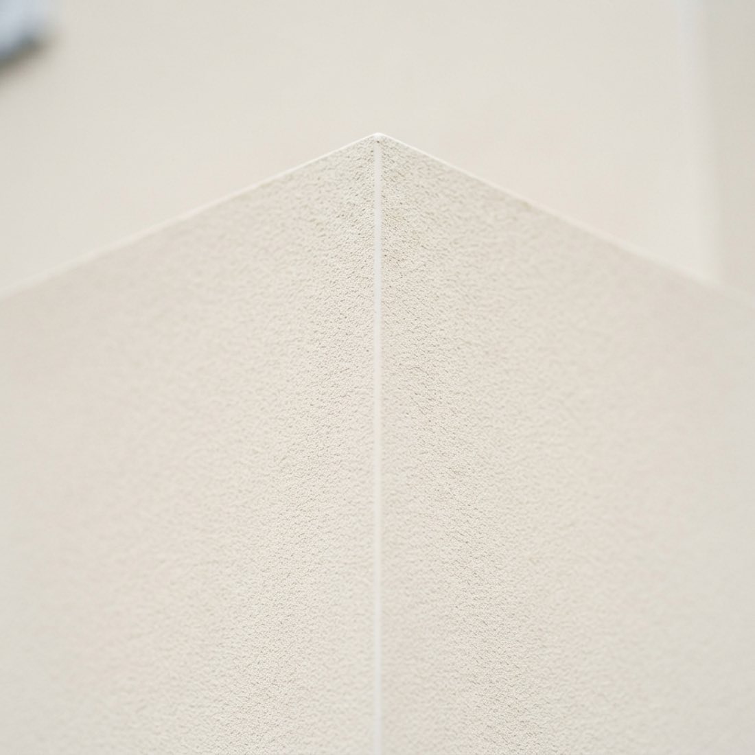 Smooth off white render in close detail, meeting at a sharp external corner.
