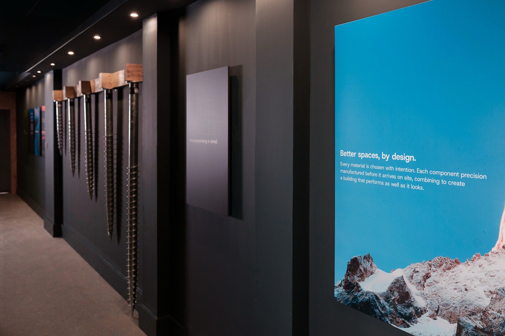 Inside the Nordu showroom near Glasgow, with ground screw foundations
                  displayed along a dark wall beside a lit graphic panel.